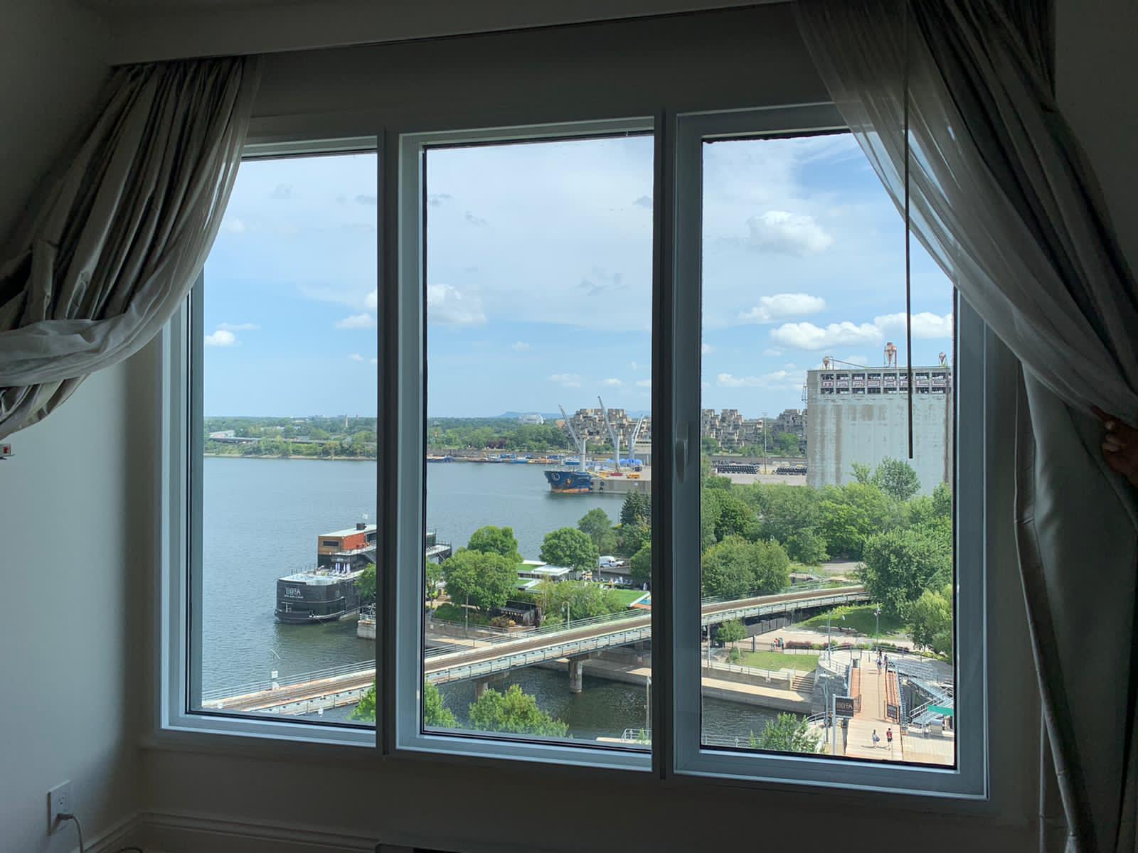 Wide window fitted with a clear acrylic panel, a river and parkland visible beyond the glass