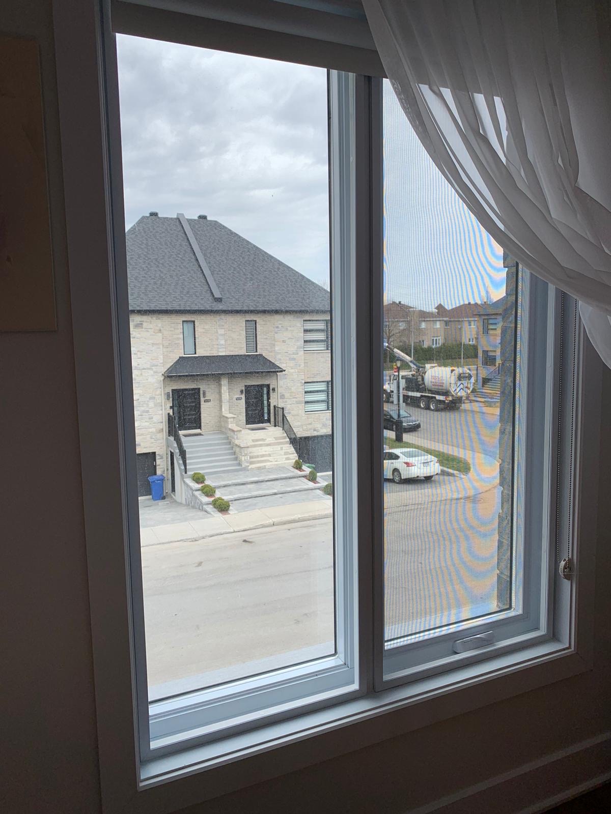 A transparent Insulatx acrylic panel installed over an existing window facing a street